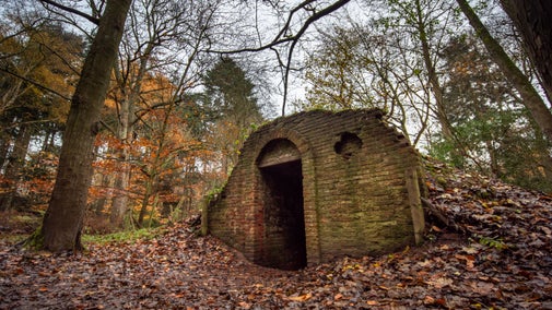 The Ice House in the Great Wood surrounded by fallen autumn leaves. It was built with bricks in the 18th century to look like a ruin.
